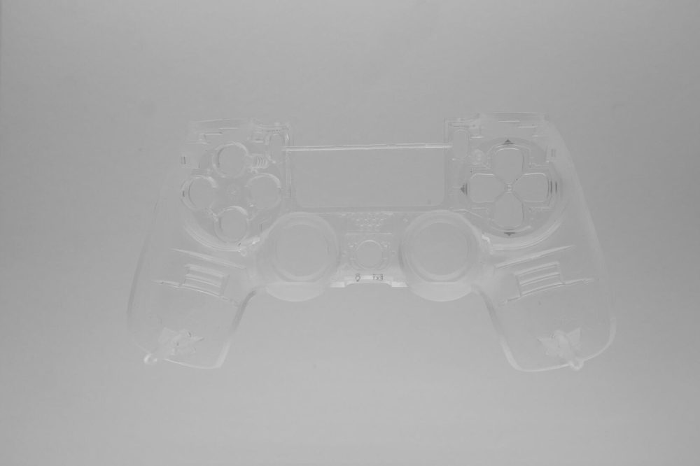Ein durchsichtiges PS4 Front Case transparentes Gehäuse JDM040 ist vor einem schlichten, hellgrauen Hintergrund zentriert und erinnert an den ikonischen PlayStation-Stil.