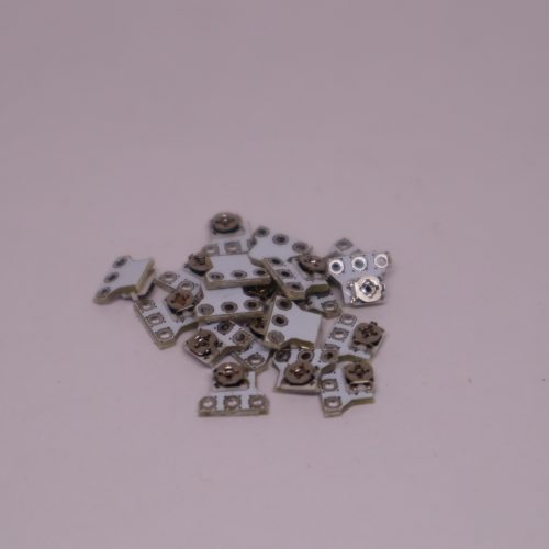 Ein kleiner Haufen metallischer Stick neu kalibrieren Modul-Komponenten ist auf einer hellrosa Oberfläche verstreut und erinnert an die winzigen Teile im Inneren eines PS5-Controllers.